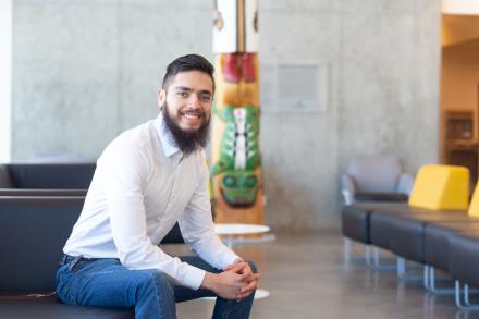 Fernando sits near the totem inside the Centre for Health and Science, VIU's Nanaimo campus