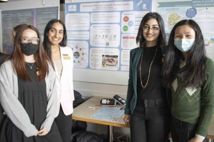 Four students standing in front of a poster