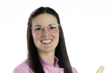 Kate Wilson in a baking uniform holding a rolling pin