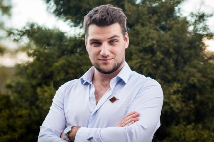 Portrait of Jonah with arms crossed in front of greenery