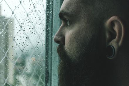 Man staring out the window at the rain