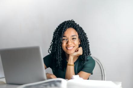 Girl looking up from laptop and smiling at the camera