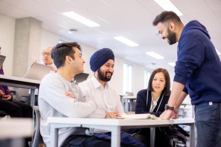 Four students interact around a desk