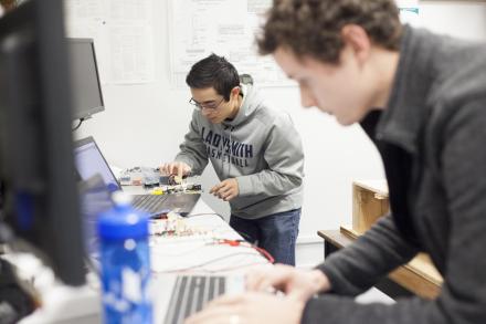 Two VIU Engineering students work on computer equipment in a lab.